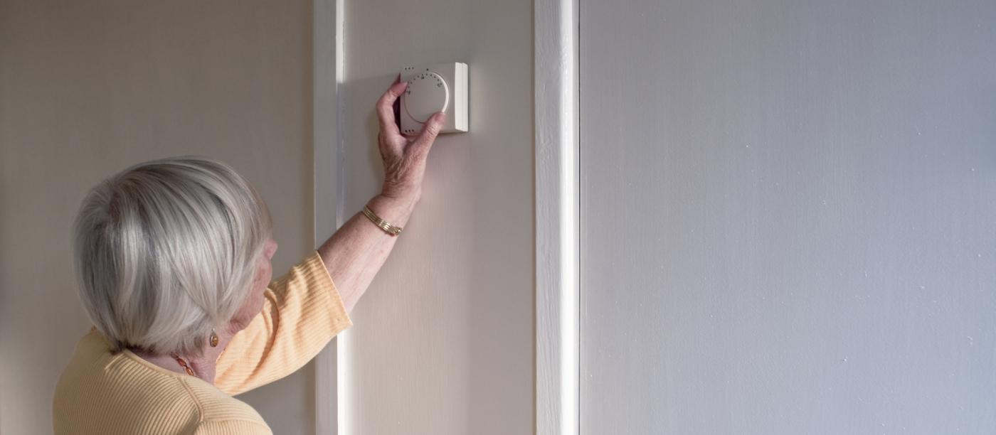 women turning down a thermostat